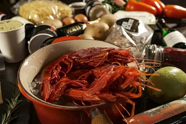 Pranzzo Rote Garnelen in einem Topf auf Eis, umgeben von frischen Zutaten und Küchenutensilien.