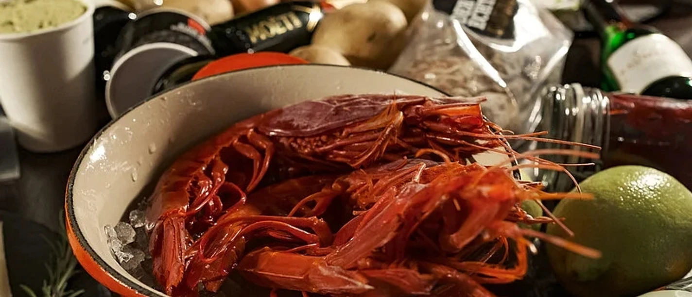 Pranzzo Rote Garnelen in einem Topf auf Eis, umgeben von frischen Zutaten und Küchenutensilien.