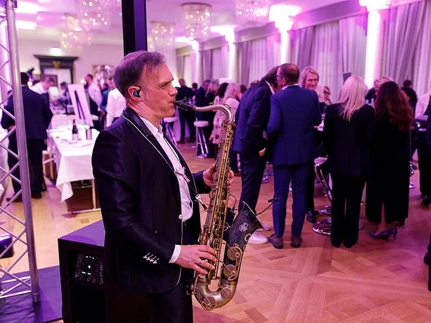 Falstaff Weintrophy Saxophonist spielt bei festlicher Veranstaltung in elegantem Saal.