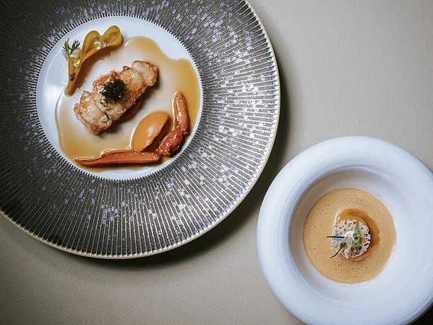 Althoff Modern Chefs Circle Zwei kunstvoll angerichtete Gourmetgerichte auf eleganten Tellern in moderner Präsentation.