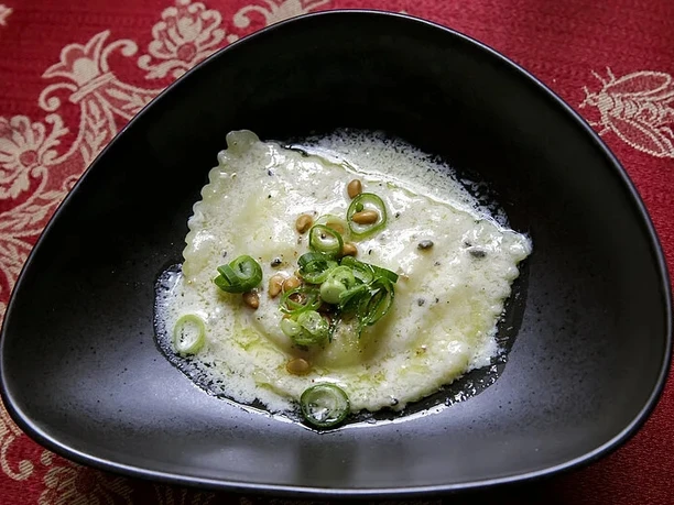 Dinner and Concert Riesige Ravioli in Butter-Sahnesauce mit Lauch und Pinienkernen in schwarzer Schale