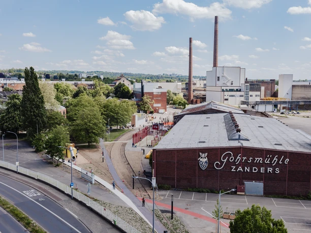 109 - 7G7A9674.jpg Blick auf Werksgebäude und Grünflächen am Gleispark mit Wegen und Spielbereich