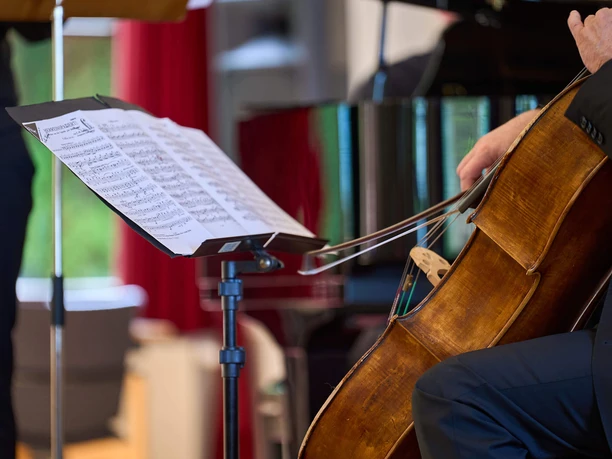 Kurkonzert-Spiegelsaal-Bad-Zwischenahn2.jpg Ein Musiker spielt Cello. Im Fokus steht ein Notenständer mit aufgeschlagenen Noten.