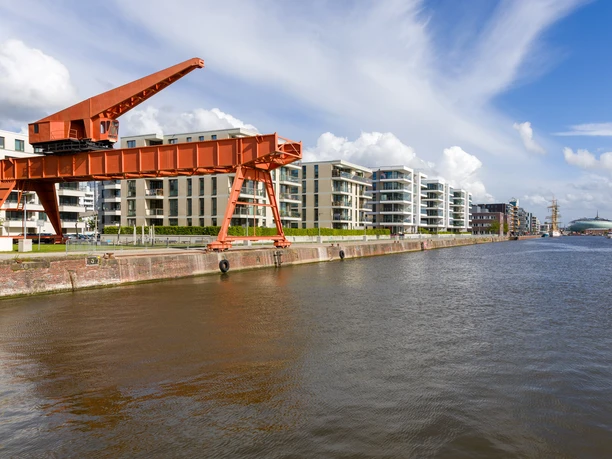 S8346 (c) Helmut Gross_Erlebnis Bremerhaven_WEB.jpg Roter Kiesverladekran am Alten Hafen in Bremerhaven vor modernen Gebäuden.