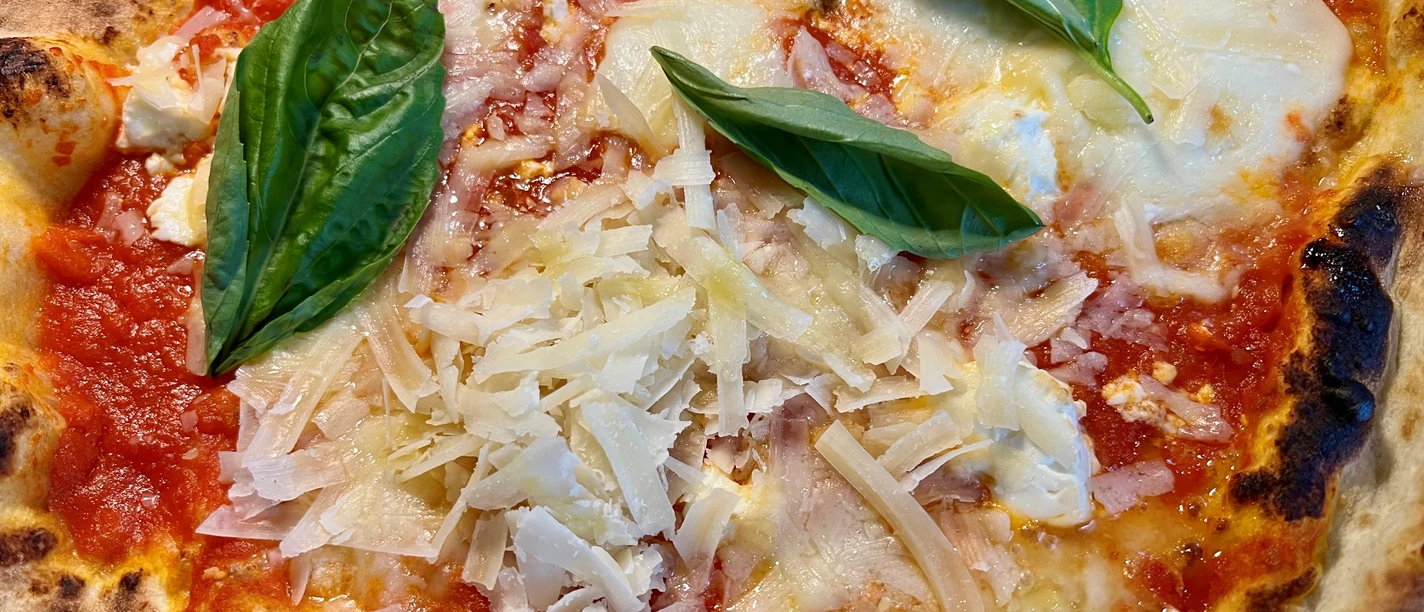 Pizza Pizza mit Tomatensoße, geschmolzenem Käse, Parmesanspänen und frischem Basilikum.