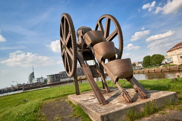 Stadtansichten von Bremerhaven Rostiger Eimerkettenbagger als Industriedenkmal am Ufer vor der Skyline von Bremerhaven.