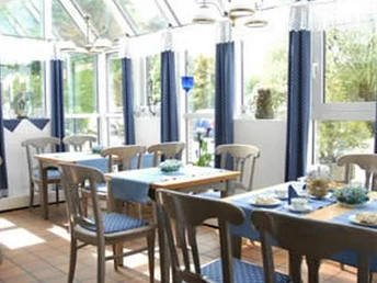 Restaurant Hotel zur Post ein Wintergarten mit Stühlen und gedeckten Tischen mit blauen Tischdecken