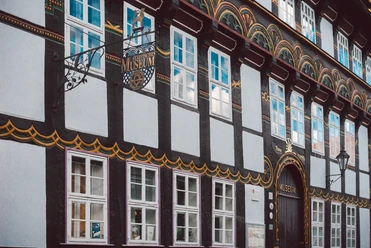 StadtMuseum 3, Einbeck - CC0.jpg Bunt verzierte Fachwerkfassade des Städtischen Museums Einbeck mit schmiedeeisernem Schild.