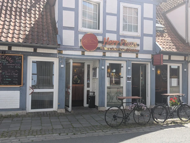Eingang zum Restaurant Herr Phan im blau-weißen Fachwerkhaus mit Menütafel und Fahrrädern.