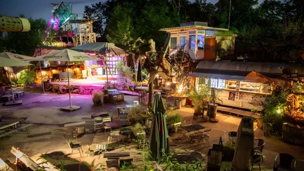 Odonien beer garden Illuminated outdoor area with metal sculptures, stage and seating in a creative ambience