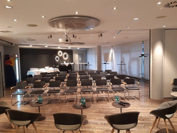 Raum 4 Kino Moderner Konferenzraum mit Stuhlreihen, Projektor und vorbereitetem Cateringbereich.