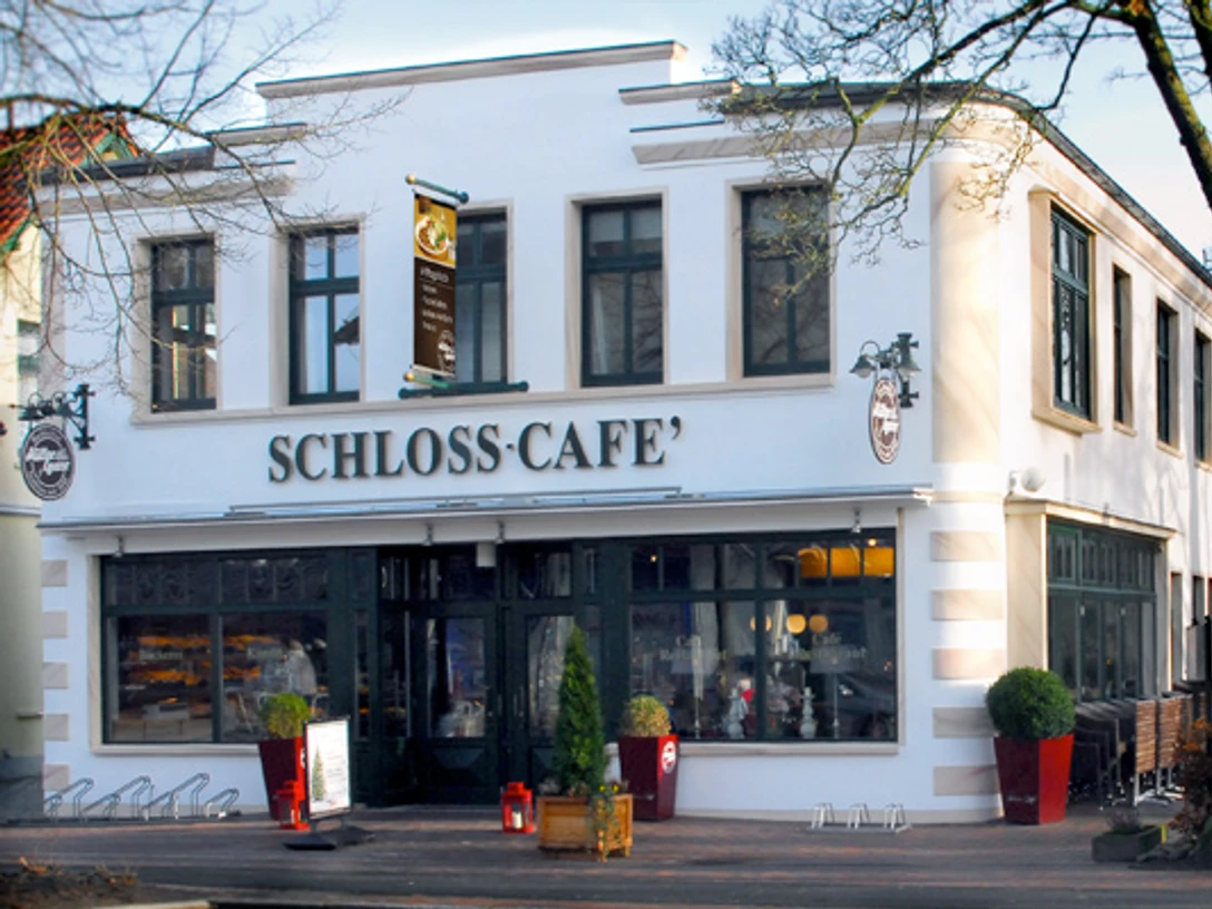 Aussenaufnahme vom Schloss-Café Zweistöckiges Gebäude mit heller Fassade und großen Fenstern, Eingang zum Schloss-Café.