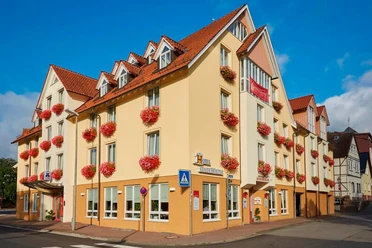 hotel-stadthoexter-hausansicht-c-marcusbrodt Außenansicht des dreistöckigen Hotels in Gelbtönen gestrichen mit Blumenkästen an den Fenstern