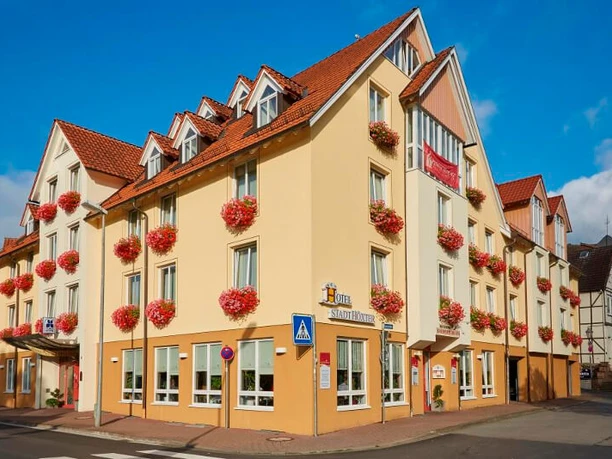 hotel-stadthoexter-hausansicht-c-marcusbrodt Außenansicht des dreistöckigen Hotels in Gelbtönen gestrichen mit Blumenkästen an den Fenstern