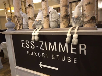 hotel-niedersachsen-restaurant-huxoristube1 Hinweisschild zur Huxori-Stube mit Dekobirkenstämmen und Zwergen zur Deko