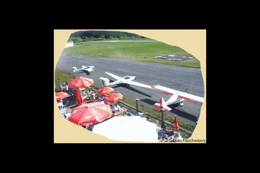 ab_cafeamraeuschenberg_terrasse.jpg Sonnenterrasse mit Sonnenschirmen und Flugzeuge in Parkposition