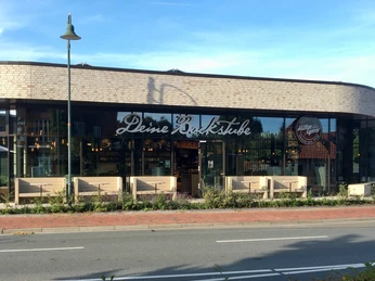 Müller & Egerer Bild einer Bäckerei mit dem Schriftzug "Deine Backstube" und einladenden Sitzgelegenheiten davor.