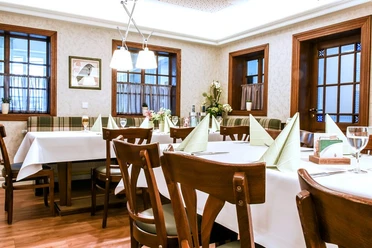 fs-raum Ein stilvoll eingerichtetes Restaurant mit gedeckten Tischen, gemütlichen Holzmöbeln und eleganter Beleuchtung.