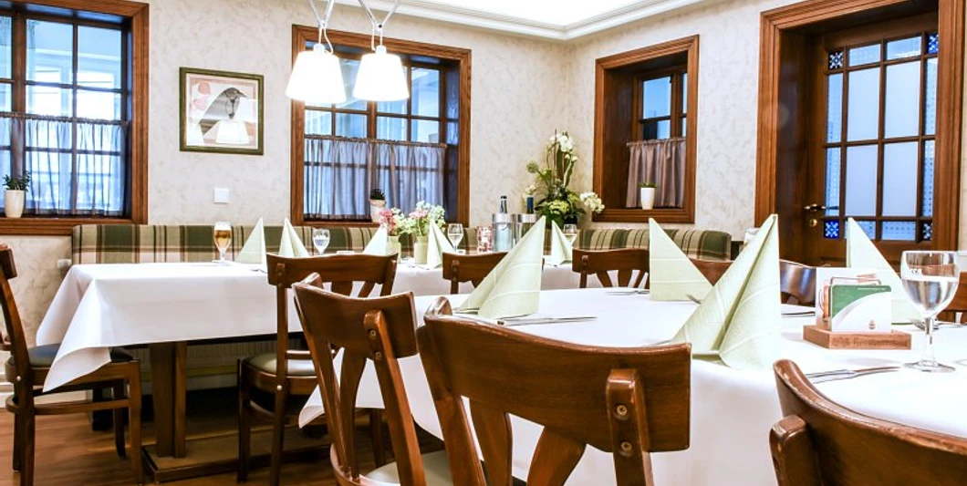 fs-raum Ein stilvoll eingerichtetes Restaurant mit gedeckten Tischen, gemütlichen Holzmöbeln und eleganter Beleuchtung.