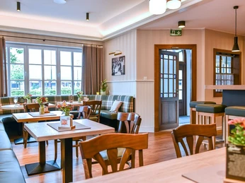 wirtschaft-offen Gemütliche Gaststube mit Holztischen, Stühlen und Dekoration, helle Fenster im Hintergrund.