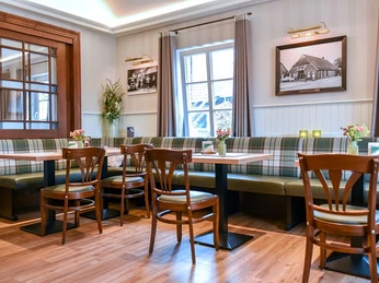 wirtschaft-st-tisch Gemütlicher Raum in einem Restaurant mit Holzboden, Fenster, Tischen, Stühlen und Dekorationen.