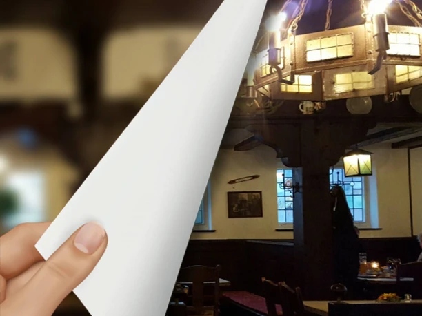 Schweers Harms Fischerhus Ein rustikales Gasthausinterieur mit hölzernen Deckenbalken und einem markanten Kronleuchter.