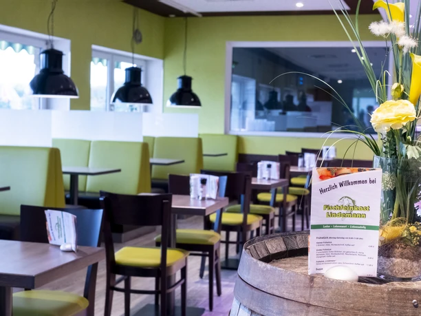 A modern restaurant with bright, green benches and a flower arrangement.