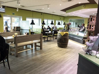 Fischfeinkost Lindemann Restaurant II Einladendes Restaurant mit Holzbänken und gelb-grüner Dekoration, Gäste sitzen an Tischen.