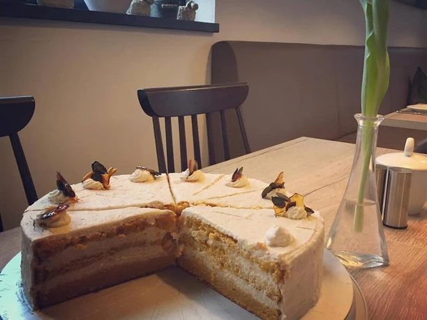 Sahnetorte Eine angeschnittene Sahnetorte mit Schichten auf einem Teller in einem Café mit Vase im Hintergrund.
