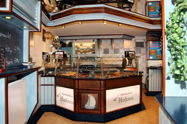 Interior view of the eel smokehouse with glass sales counter, presenting various fish products.