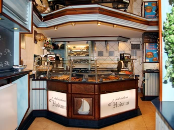 Fischerei & Aalräucherei Hodann GmbH Innenansicht der Aalräucherei mit gläserner Verkaufstheke, präsentiert verschiedene Fischprodukte.