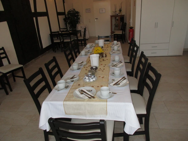 A long table in a café is festively laid with a white tablecloth, crockery and decorations.