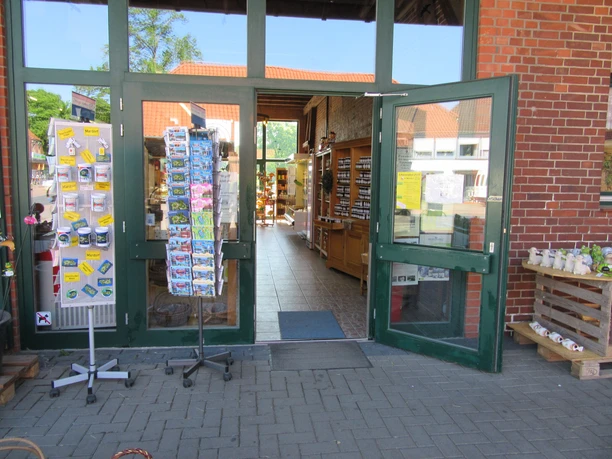 Eingang-Hofladen-Niemeyer Der Eingangsbereich eines Hofladens mit offenen Türen, innen sind Regale mit Produkten zu sehen.