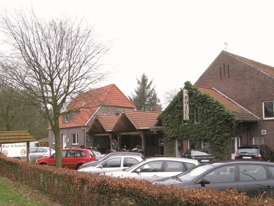 Aussenansicht Gaststätte Zur Schanze Die Außenansicht der Gaststätte "Zur Schanze" zeigt ein einladendes, von Efeu bewachsenes Gebäude mit Parkplätze davor.