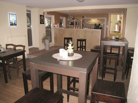 Thekenbereich Der Thekenbereich in einem gemütlichen Lokal, mit Holzstühlen und kleinen Pflanzen dekoriert.