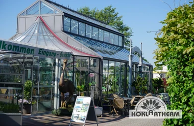 Orangerie Außenansicht Die Orangerie zeigt eine moderne, gläserne Fassade mit Pflanzen im Eingangsbereich.