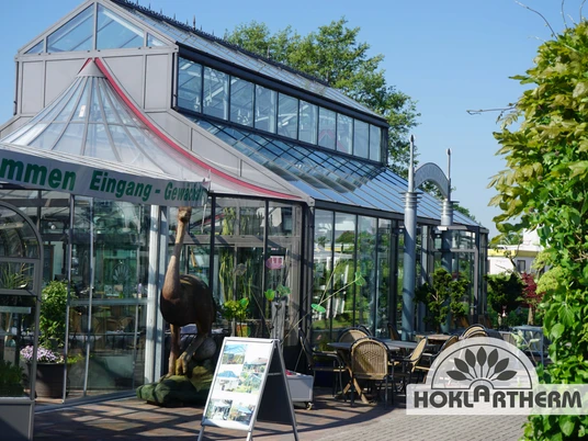 Orangerie Außenansicht Die Orangerie zeigt eine moderne, gläserne Fassade mit Pflanzen im Eingangsbereich.