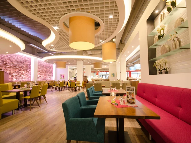 Cosy bistro with modern furnishings: colorful upholstered furniture, warm lighting and stylish wall decorations. Perfect for relaxed breaks in an urban ambience.