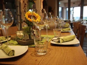 Bäckerei Ripken Rustikales Café-Ambiente mit gedecktem, hölzernem Tisch, grünen Servietten und frischen Sonnenblumen.Rustic café ambience with a wooden table setting, green napkins and fresh sunflowers.Rustik caféstemning med borddækning i træ, grønne servietter og friske solsikker.Rustieke caféambiance met een houten tafeldekking, groene servetten en verse zonnebloemen.