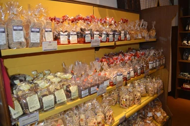 Keksgalerie im Schulze Ladencafé, Borgholzhausen Verschiedene Sorten von Keksen in durchsichtigen Tüten auf gelben Regalen in einem Ladencafé.