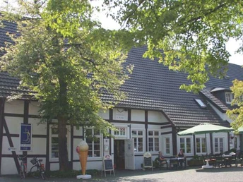 Fachwerkhaus im Grünen, mit Eisdiele im Vordergrund und einladenden Sitzmöglichkeiten im Freien.