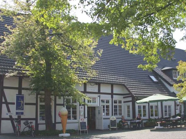 Café zur Linde Fachwerkhaus im Grünen, mit Eisdiele im Vordergrund und einladenden Sitzmöglichkeiten im Freien.