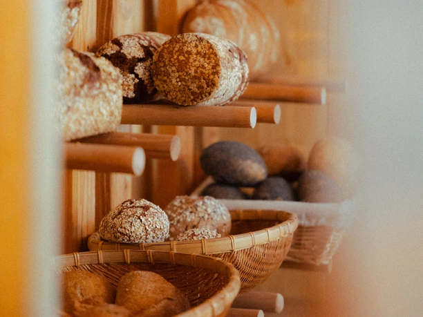 Findus 2 (c) Quang_WEB.jpg Frische, rustikale Brote und Brötchen mit Körnern in einem Regal aus Holz.