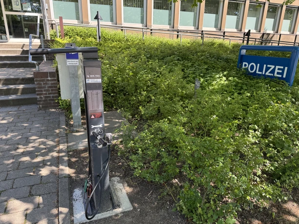 Radservicestation Schwarzenbek (Polizei) Outdoor bike repair station beside a police building near steps and surrounding greenery.