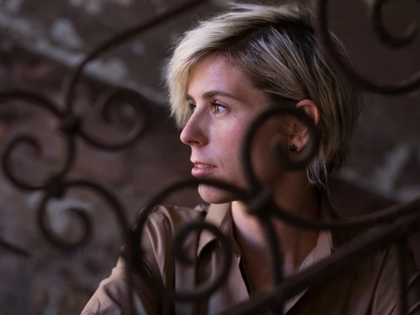 flora Fabri Portrait of a person behind curved metal, looking sideways in warm light