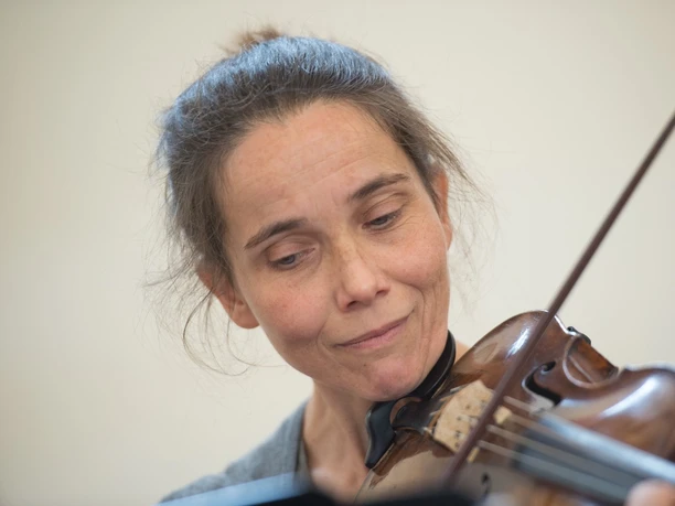 Tabea Höfer Person spielt konzentriert Geige vor hellem Hintergrund.