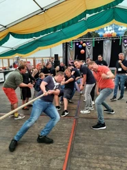 impressionen-0095-veranstaltungen-2023-verein-fest-der-1000-laternen-apen-augustfehn-Firmennachmittag.jpg Zwei Männermannschaften treten beim Tauziehen in einem Festzelt gegeneinander an.