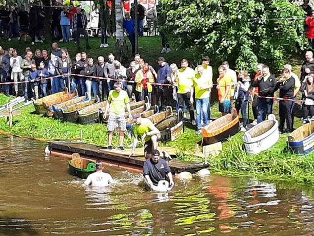 impressionen-0091-veranstaltungen-2023-verein-fest-der-1000-laternen-apen-augustfehn-Waschzuberregatta.jpg Teilnehmer der Waschzuberregatta paddeln in Holzzubern, während Zuschauer vom Ufer aus zusehen.