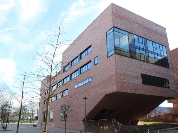 Hochschule13(c)maja_herwig.jpg Modernes Backsteingebäude der Hochschule Bremerhaven mit auskragendem Obergeschoss und großen Fenstern.