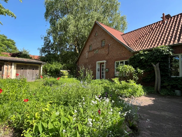 Apartment Lustiger Strump The brick building of FeWo Lustiger Strump, surrounded by a flowering garden in the sunshine.